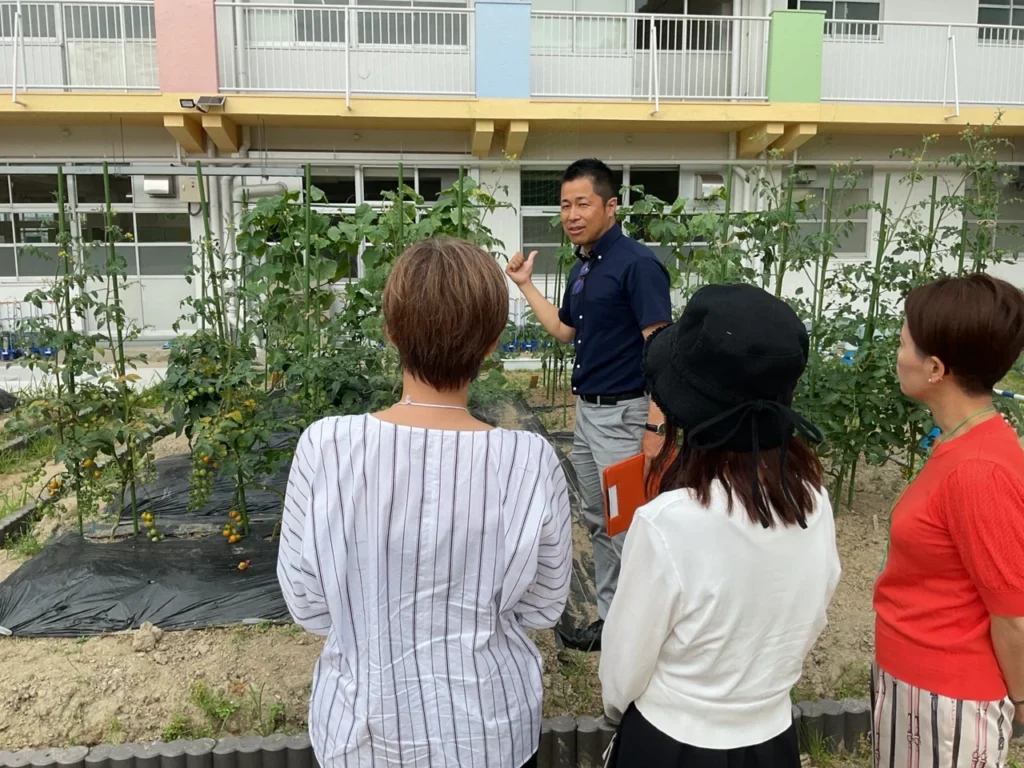 食養ファーマーズアカデミーの農園で、講師が受講生に野菜栽培や土づくりを説明している様子