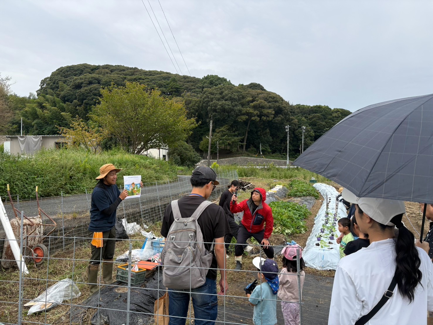 堀越の畑で教材を使い、株式会社タカギの社員とご家族に野菜作りを伝える外薗明博